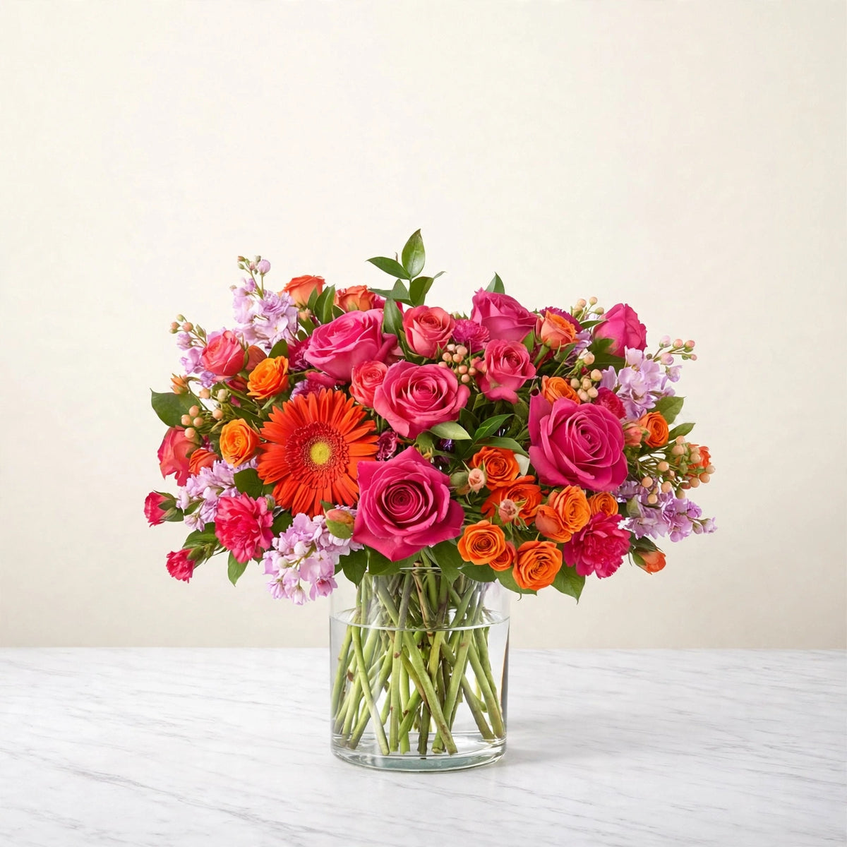 Fiesta Bouquet — orange gerbera daisies, orange and hot pink roses, pink carnations and orange spray roses in a clear glass vase, hand-arranged by LaLa Florist in Baldwin Park, fuller display view
