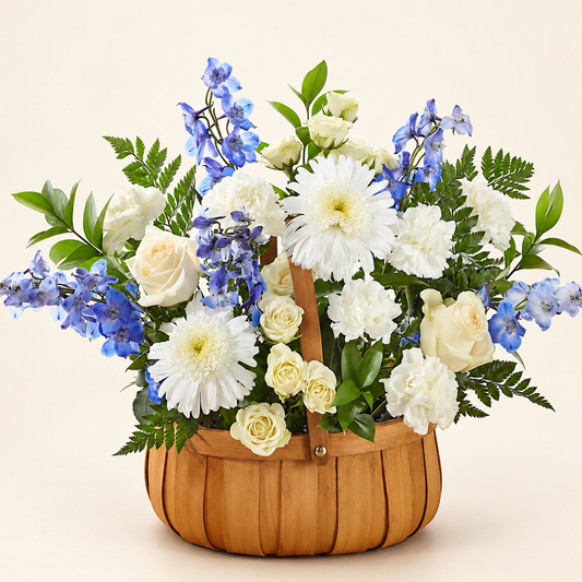 Harmony & Grace sympathy basket with white roses, blue delphinium and white carnations in a natural wicker basket, three-quarter view
