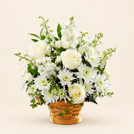 Heartfelt Condolences arrangement, all-white sympathy basket with roses, stock, cushion pompons and larkspur in a natural wicker basket, front view

