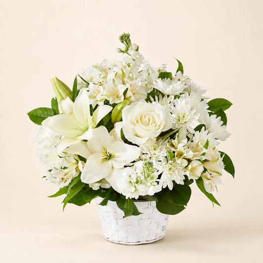 White sympathy arrangement with lilies and roses in a classic white basket