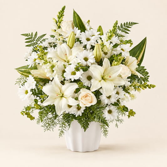 White memorial arrangement with lilies, roses, and hydrangeas in a ceramic container