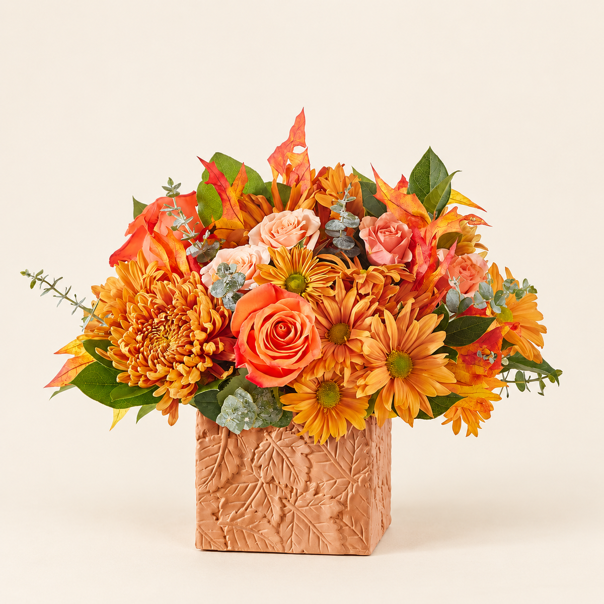 Autumn Harvest bouquet with orange roses and daisies in terracotta vase, front view
