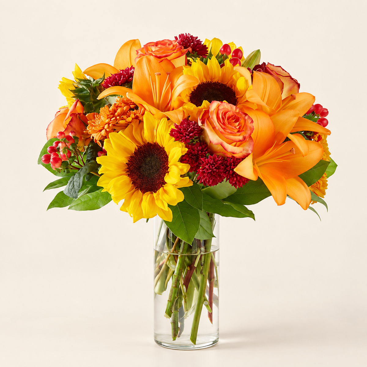 Side view of fall bouquet with sunflowers and lilies in clear vase
