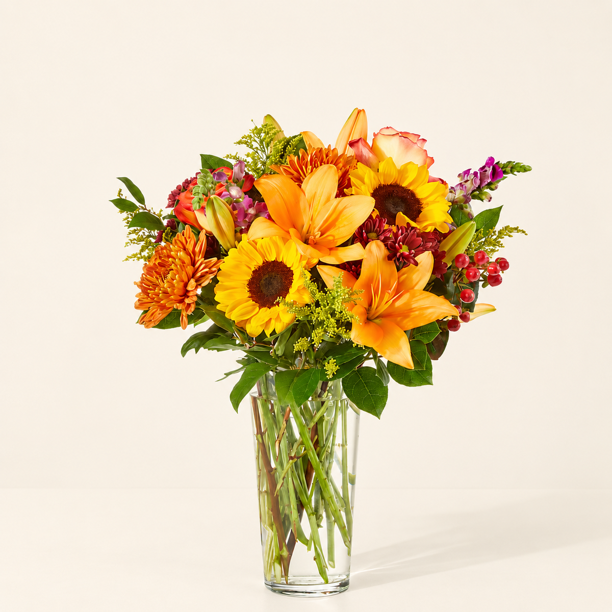 Luxurious fall bouquet with roses, lilies, and sunflowers in a glass vase, arranged by Baldwin Park florist
