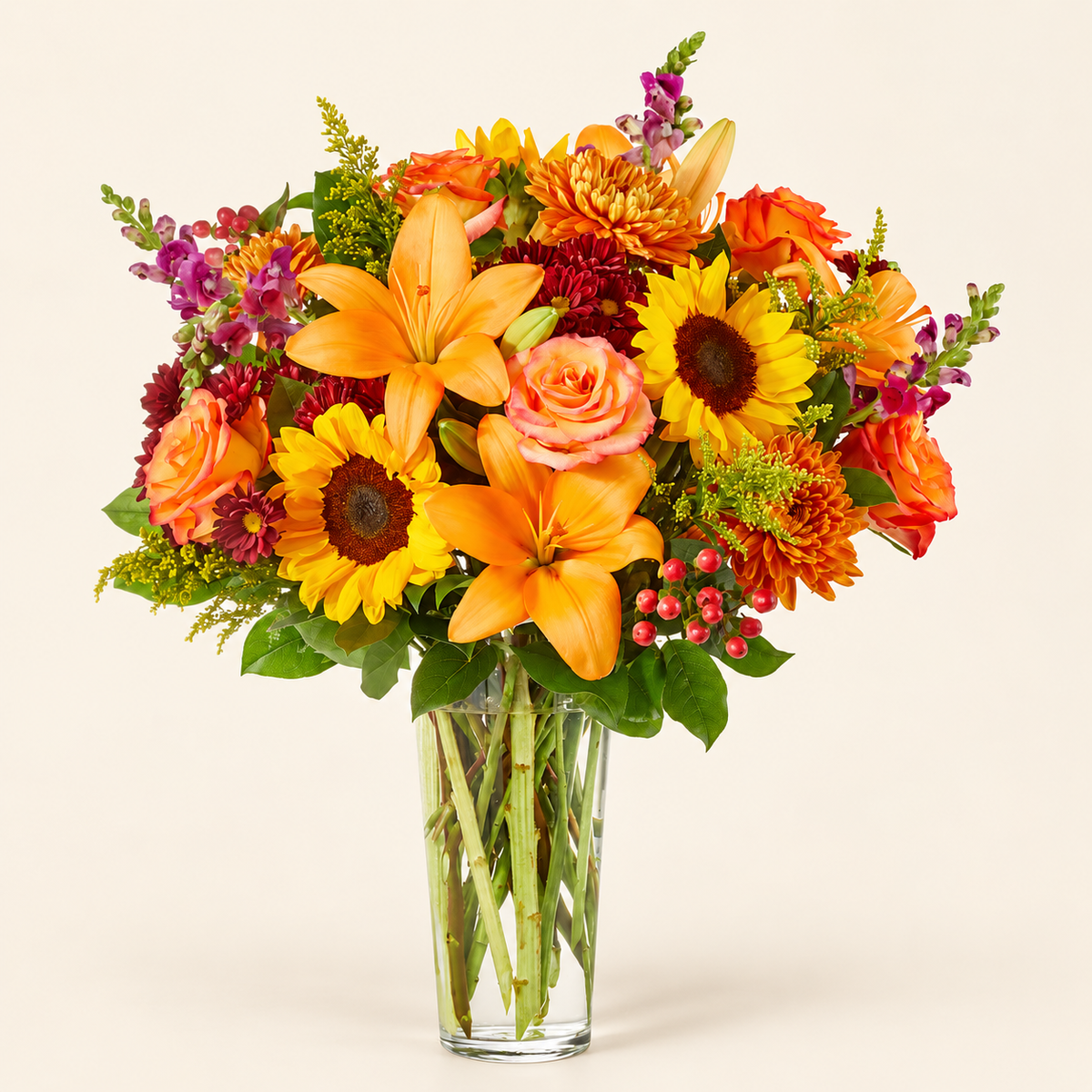 Close-up of orange lilies, sunflowers, and snapdragons in a rich autumn flower arrangement
