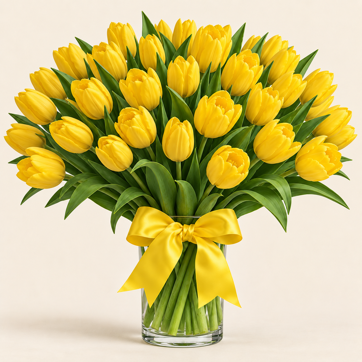 Fresh yellow tulip arrangement with yellow satin bow in clear glass vase