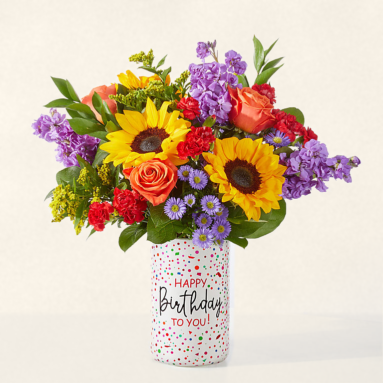 Happy birthday flower arrangement — bright sunflowers and roses in a confetti Happy Birthday to You keepsake vase