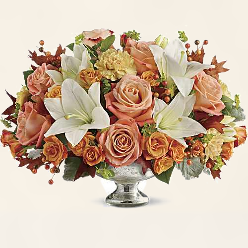 Autumn Glow centerpiece with orange roses, white lilies and fall foliage in a silver pedestal vase, hand-arranged by Baldwin Park florist