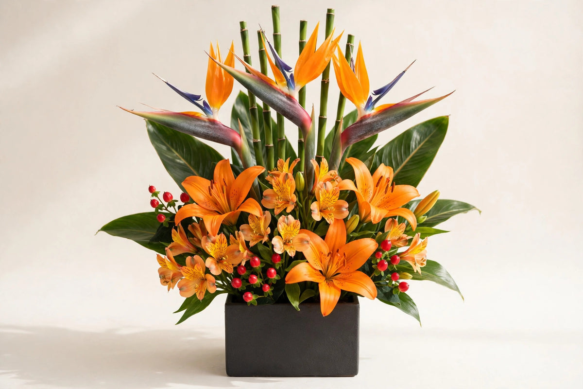 Bird of Paradise Arrangement – orange lilies and alstroemeria in a low dark container