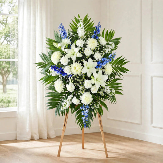 Blue Skies standing spray with white lilies, white roses, white chrysanthemums and blue delphinium on a standing easel by LaLa Florist, Baldwin Park funeral flowers