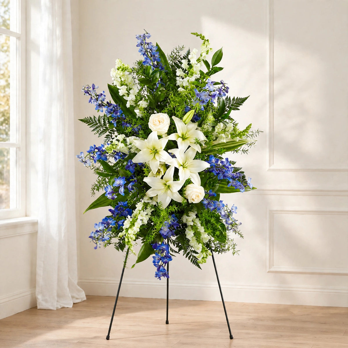 Blue & White Lily standing spray with white lilies, white roses, blue delphinium and white snapdragons on a standing easel by LaLa Florist, Baldwin Park funeral flowers